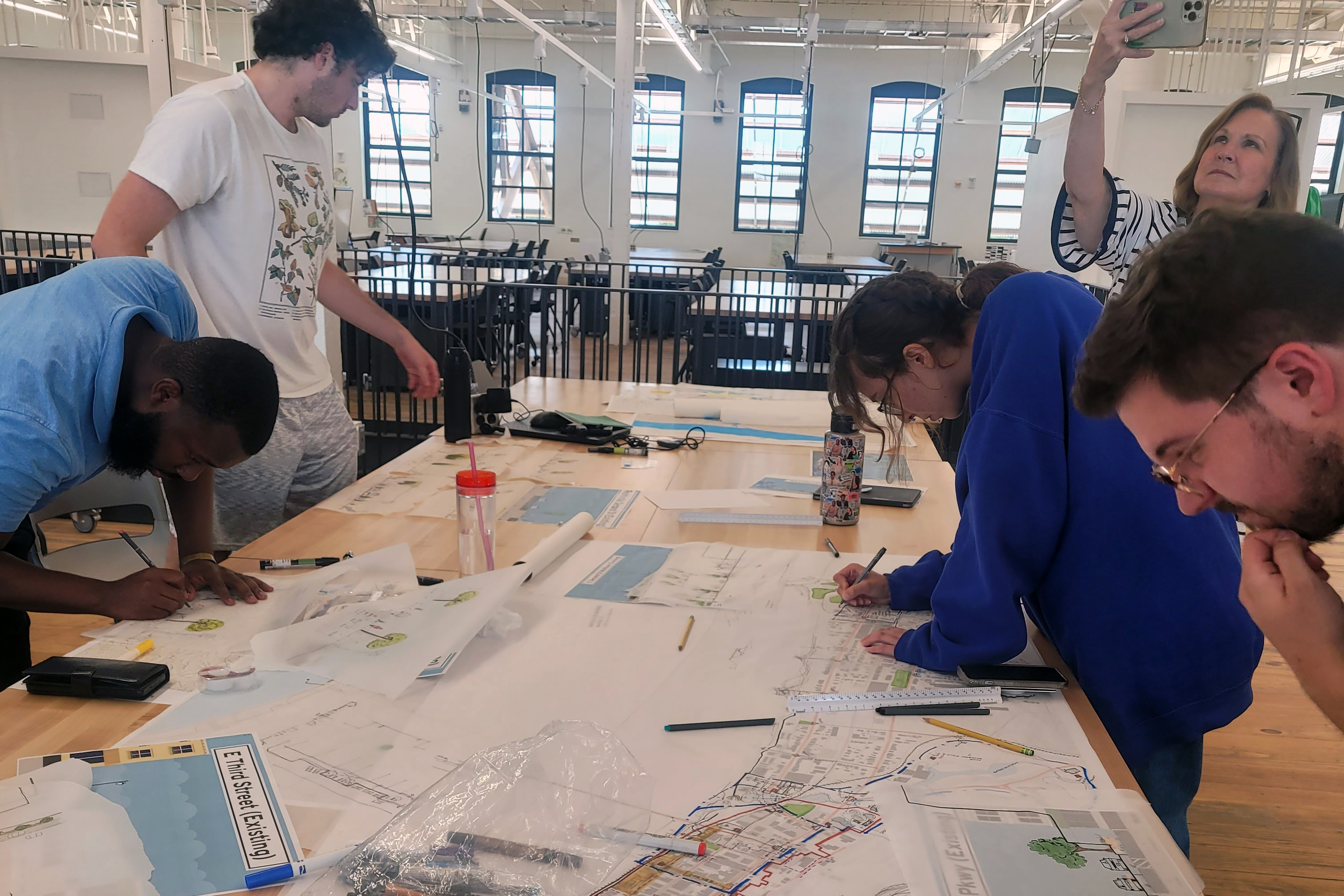 Design interns working on design plans for Maysville KY, standing around a work table