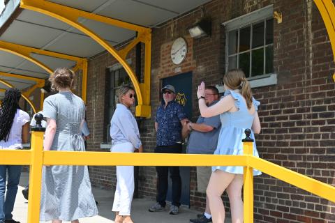 Design interns and community members standing outside the brick trainyard building in Irvine, KY