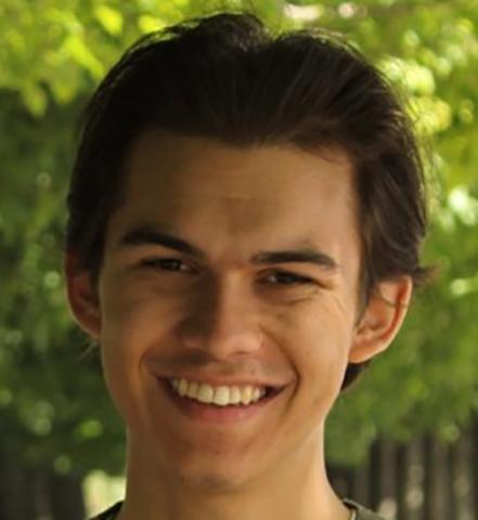 Ben Wolff's head, smiling, in front of green leafy trees